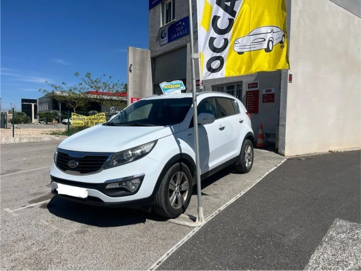 Kia Sportage blanc devant le garage FM Automobiles à Aigues-Vives